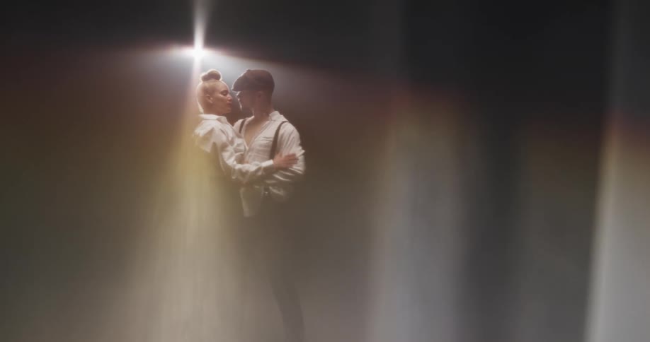 A woman approaches a man and they begin to dance under a spotlight