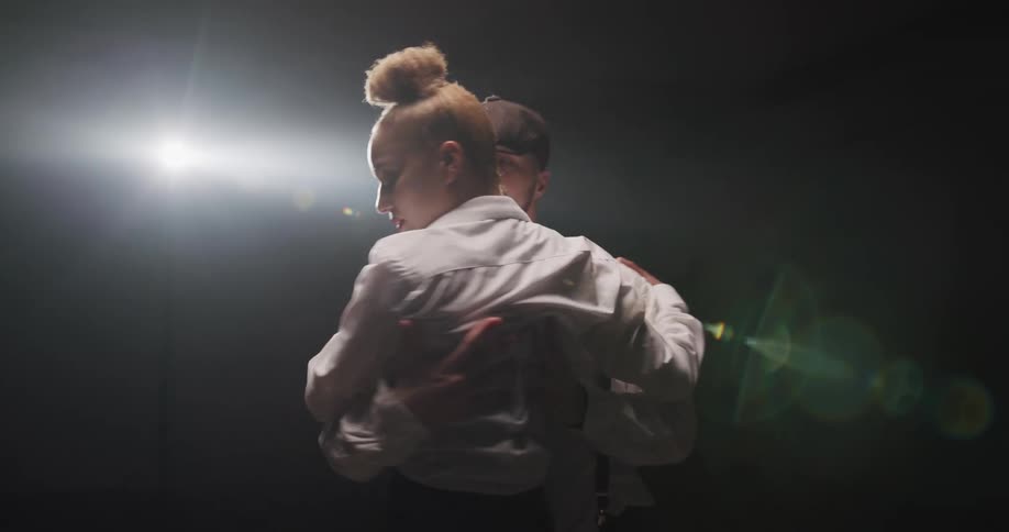A man and woman salsa dancing in front of a spotlight