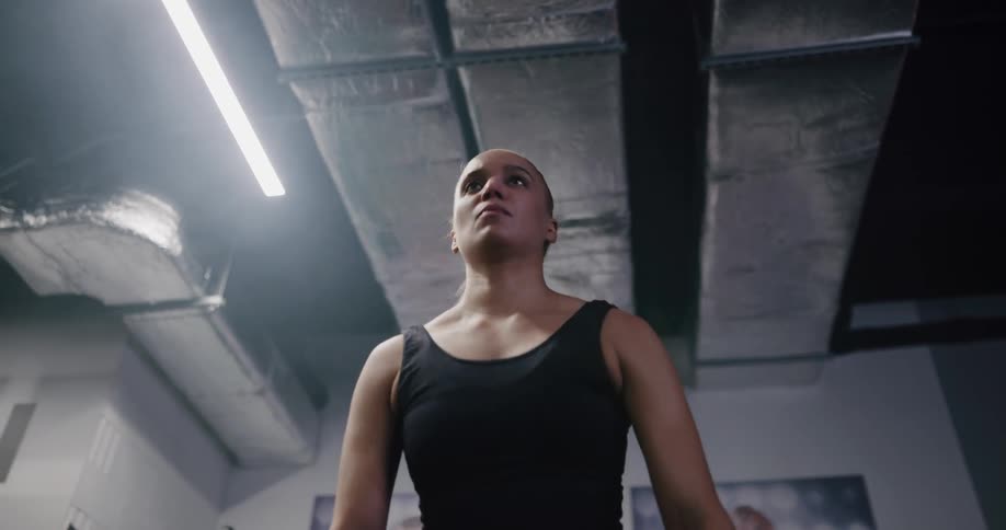 A female athlete lights a bar bell of weights to her shoulders