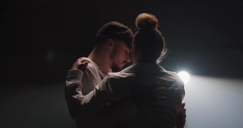 A man and woman dance on stage with a spotlight shining on them