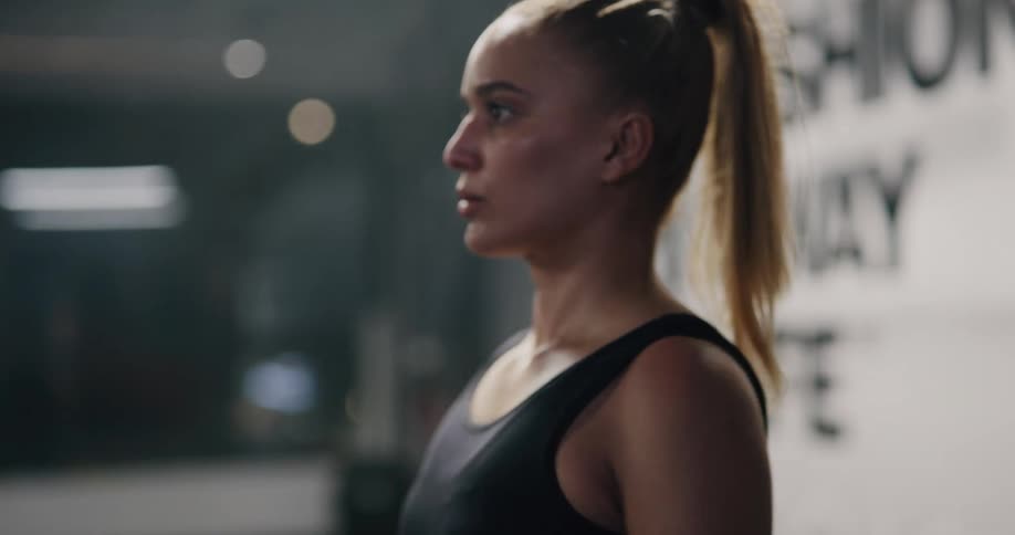 A woman is lifting a bar up to her shoulders