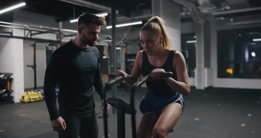A woman breathing hard while exercising on a stationary bike in a gym