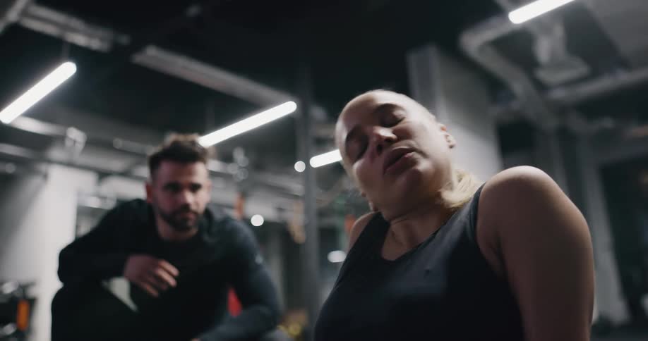 A man and woman working out with kettle bells in a gym