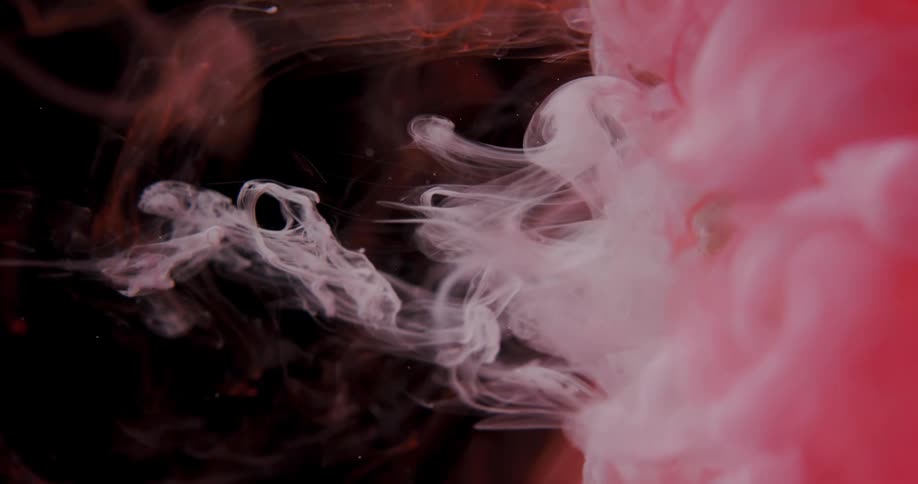 Pink and white smoke is blasted onto a pinecone surrounded by bright red smoke