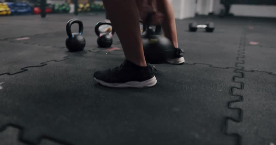 A woman training with dumbbells inside a gym at night