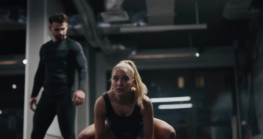 A woman working out while a man spots