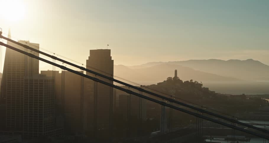 A bridge with a city skyline with buildings and skyscrapers with the sky and clouds in the background