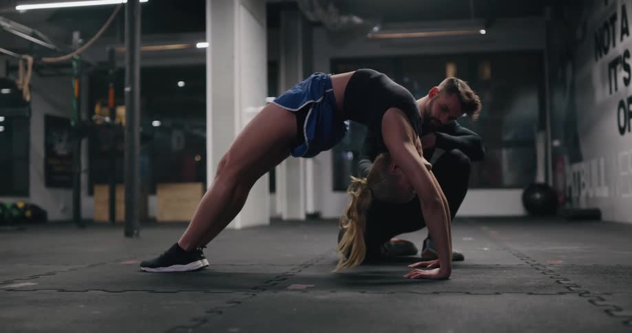 A man watches a teenage girl do a backbend and then helps her down and she stretches