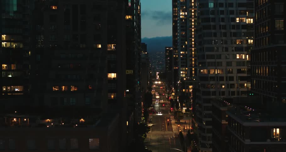 City traffic passes by tall office buildings and apartments lit up at night