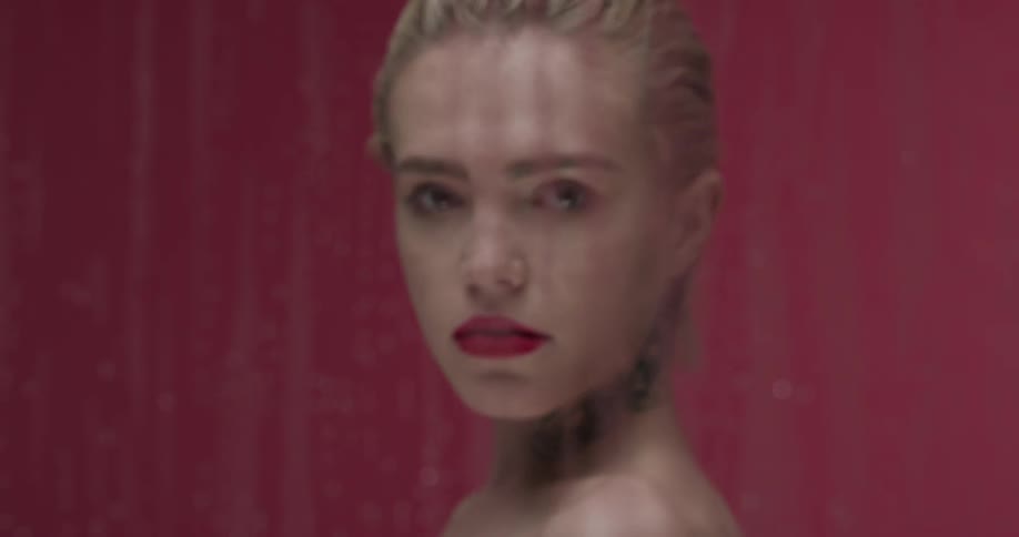 A woman is standing behind the wet glass