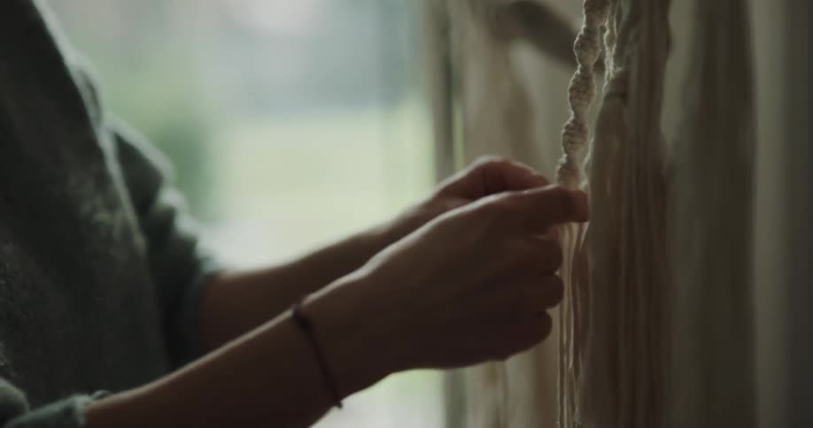 A woman weaving rope from clothes together