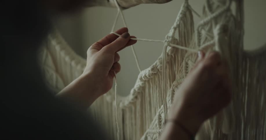 A person is designing with strings of yarn