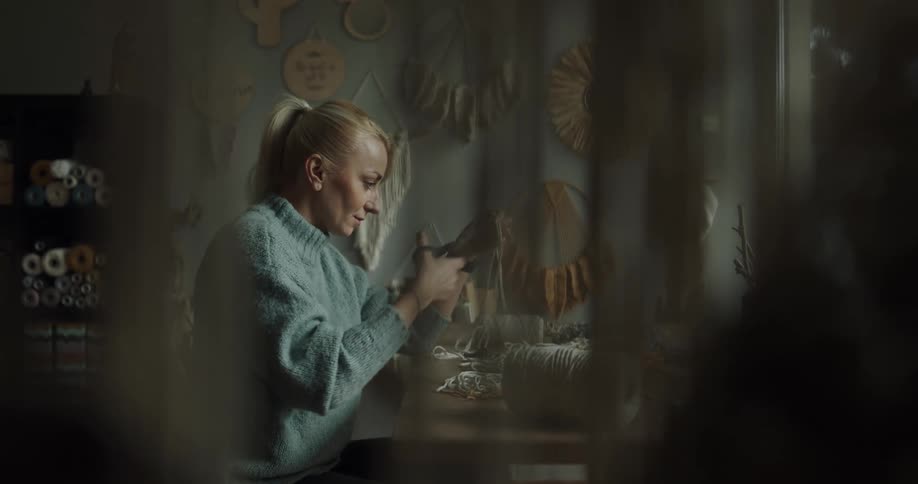 A woman is doing crafts while sitting indoors