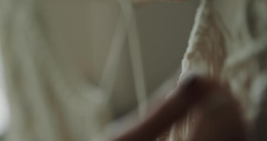 A woman weaving string into a fabric with her hands