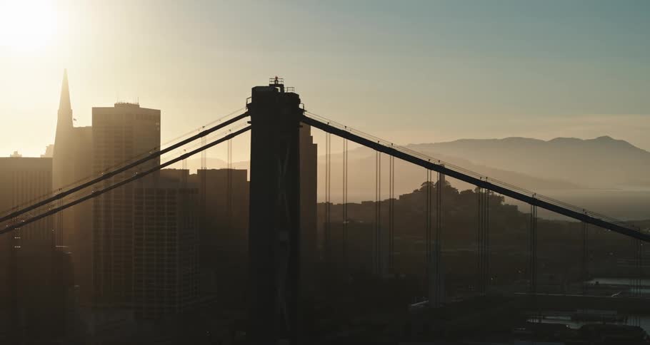 A bridge with a city skyline with buildings and skyscrapers with the sky and clouds in the background
