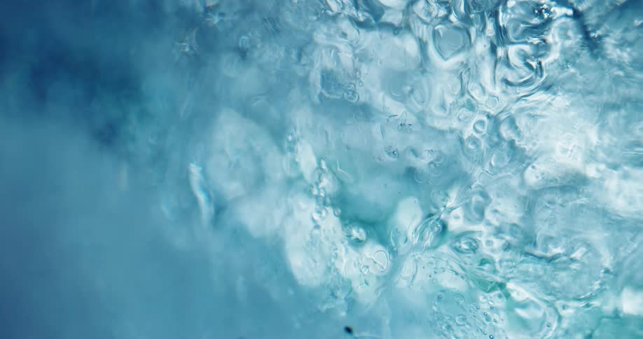 Bright blue liquid ink flowing on a surface forming abstract patterns