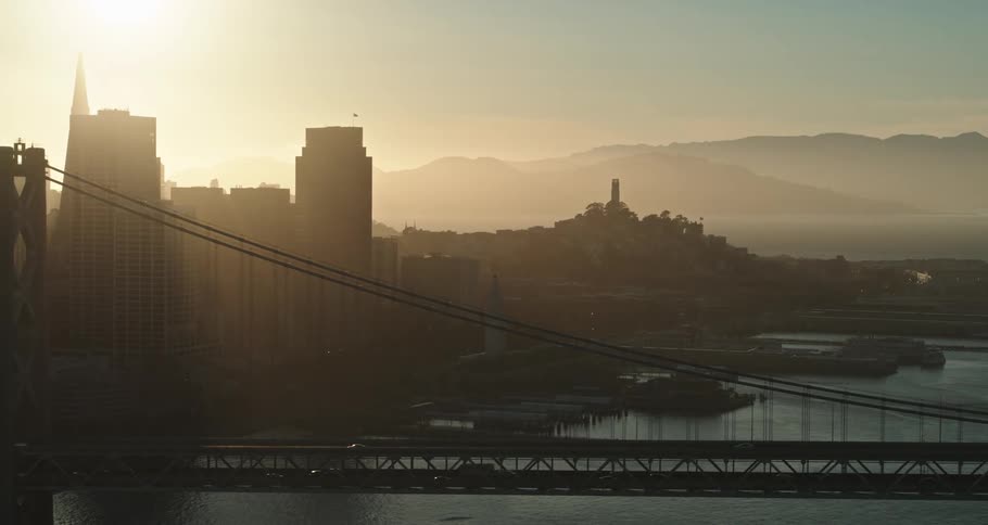 Traffic moves across a bridge with a city skyline on the waterfront