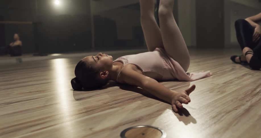 A ballet teacher training a young girl in a dance studio