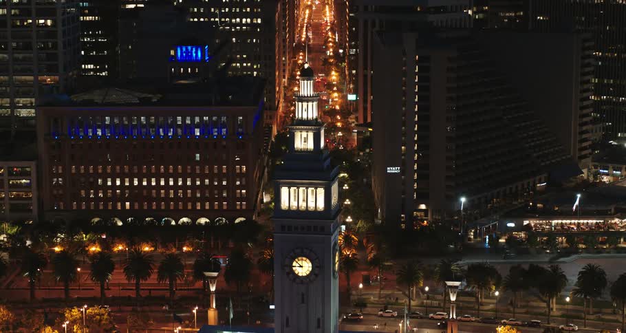 Aerial view of lit up buildings in a downtown area and traffic driving on streets