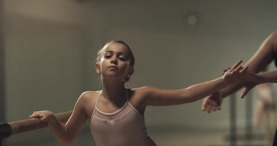 Young girl practicing ballet movements in a session with a teacher