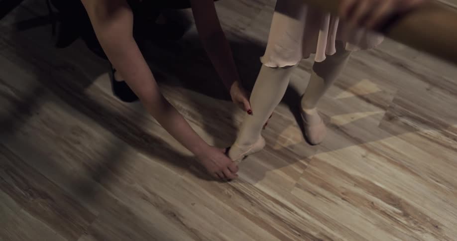 A dance instructor helps a child flex her foot