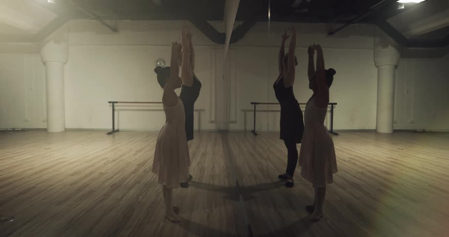 Woman teaching a girl ballet in front of a full wall mirror in a dance studio
