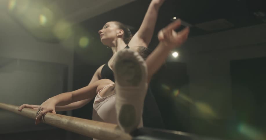 Ballet instructor teaching a young girl poses and movements on a studio