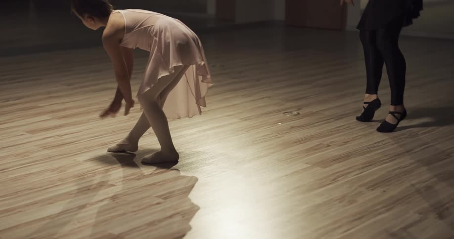 A woman teaches a girl ballet in a studio