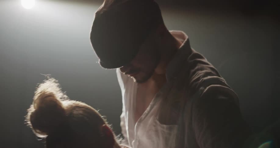 A man and woman are dancing on a stage with a spot light