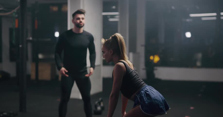 A man and woman are lifting weights in a gym