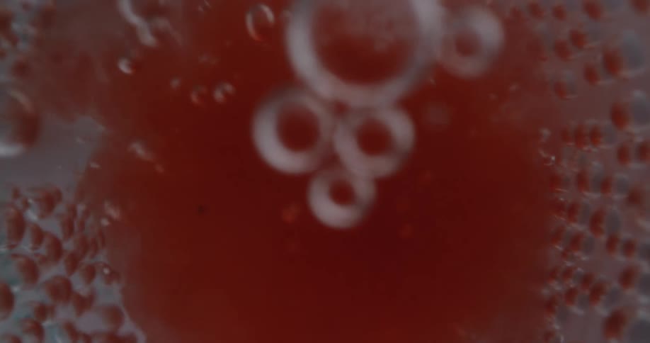 Red fluid rushes into a tube floating and bubbling