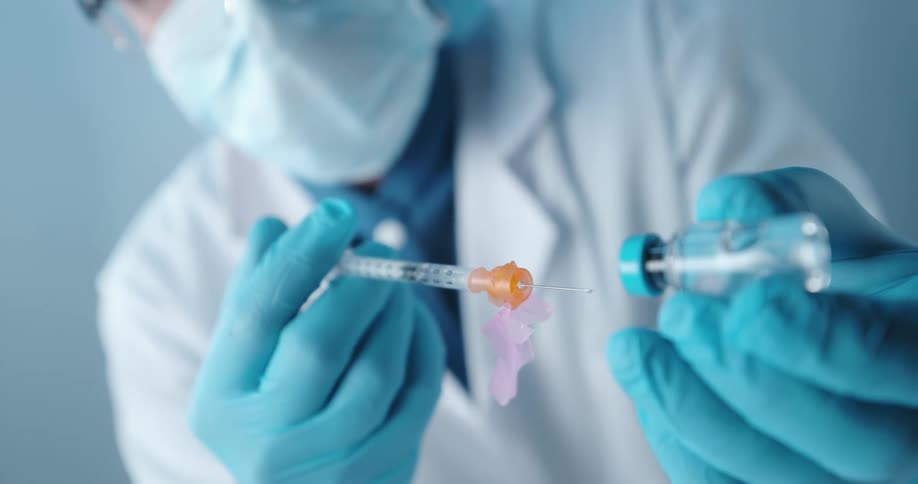 A doctor using a syringe to extract liquid from an ampoule