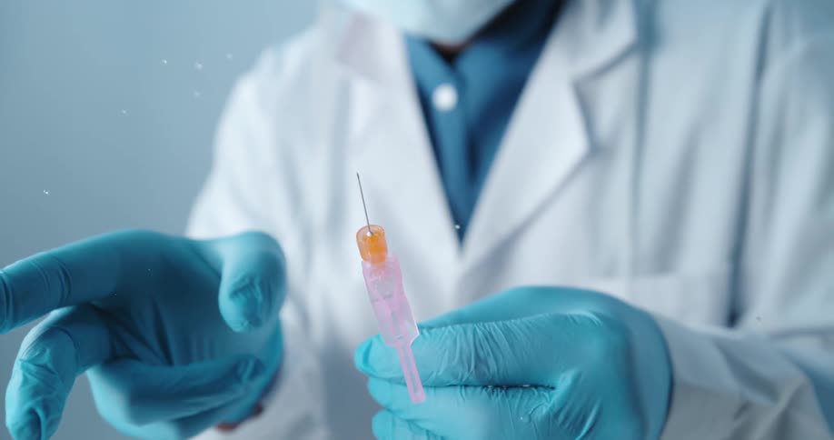 A medical staff person flicks a shot with a gloved finger