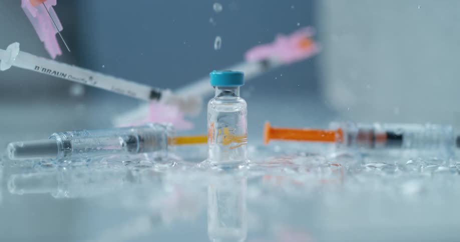 Syringes and liquid falling on counter with a small glass bottle