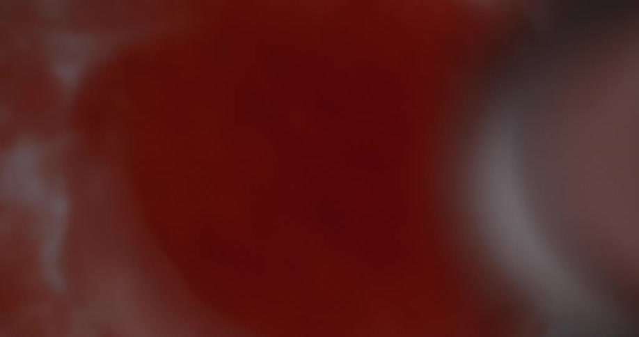 A drop of red dye being dropped into water in slow motion