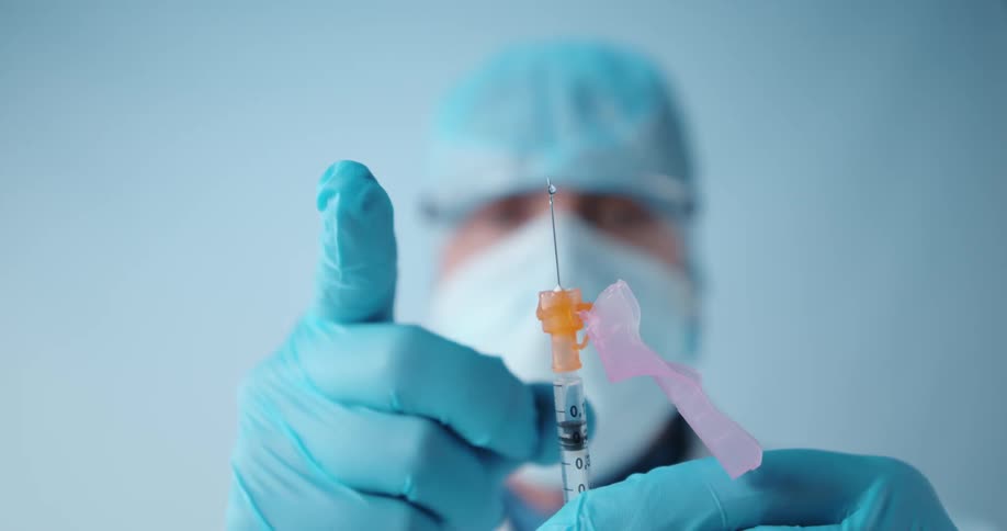 A doctor wearing gloves is holding a shot