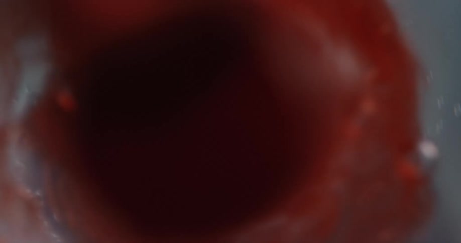 Red liquid flows through a small opening and expands