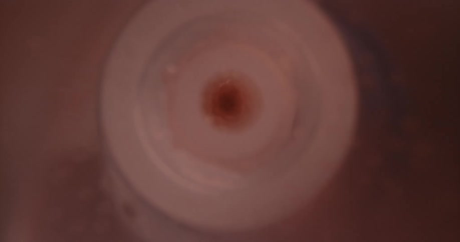 Red white and black colors that look like a plastic circle in a red liquid