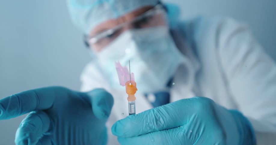 A doctor taps the end of a syringe