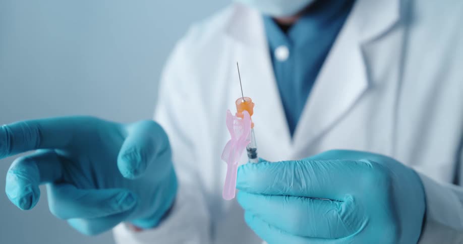 A doctor in a white lab coat flicking a loaded syringe