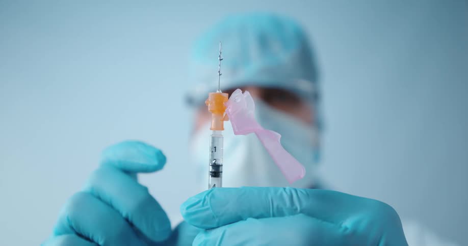 A doctor squirts a syringe in his hand