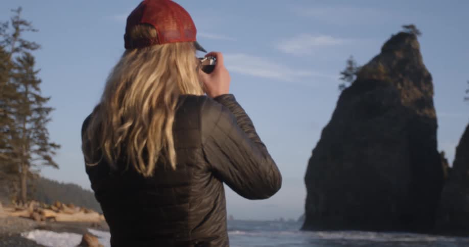 A woman photographing rock formations off the coast