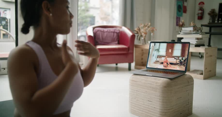 A woman sits on the floor talking to someone on a laptop video call