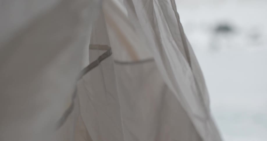 Person zipping a white tent in the snow