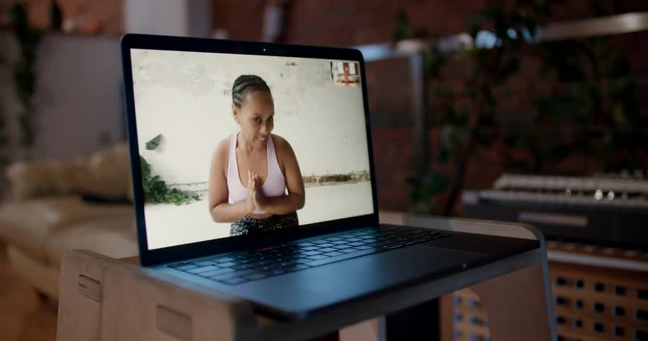 A woman in a sports bra bowing while kneeling on a computer screen