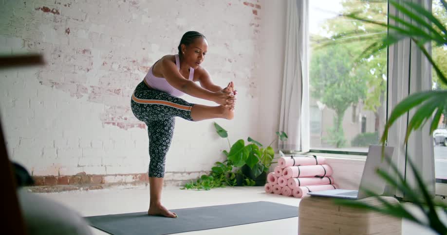 Young fit woman wearing sports clothes teaching yoga lessons online on a laptop