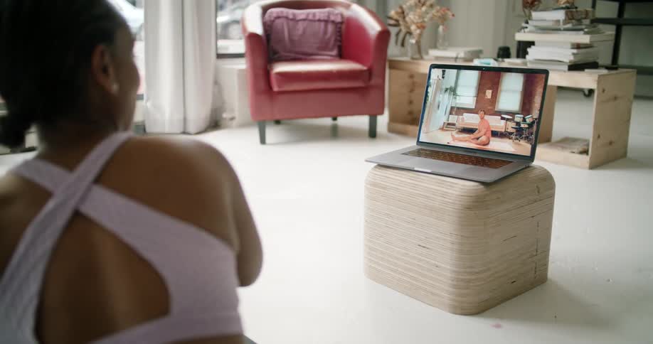 A woman doing yoga while watching it on her computer