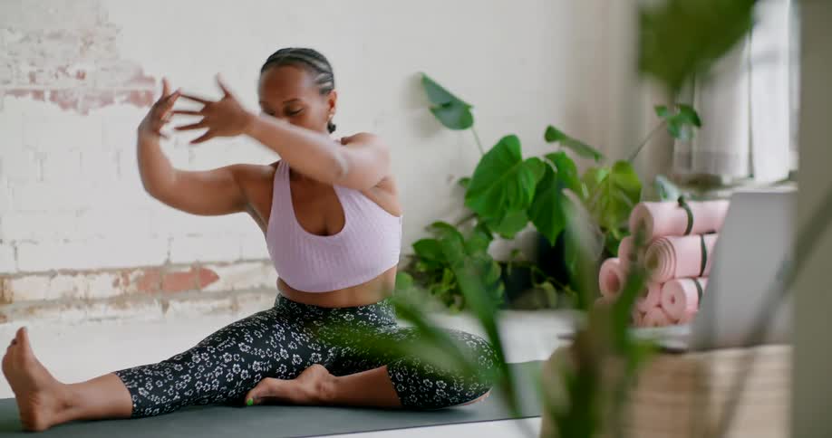 A woman in a sports bra stretching on a yoga mat indoors