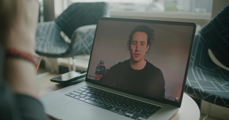 A person talking to a man that is on a laptop