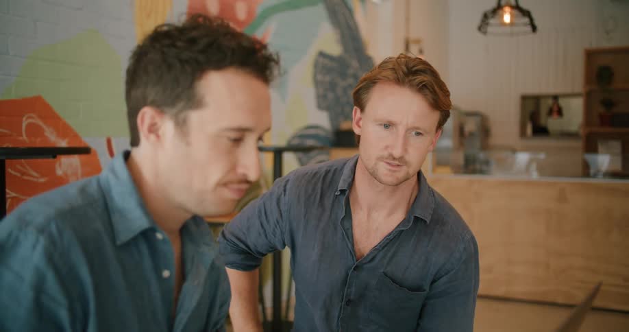 Two men having a meeting in a restaurant talking and looking at a laptop